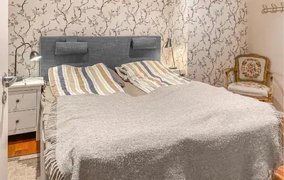 a bedroom with a large bed and a chair at Pet Friendly Home In Eidsvåg I Romsdal in Eidsvåg