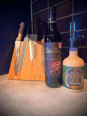 a bottle of kiwi jam and a bottle of whiskey on a cutting board at Hytte på Norefjell in Surteberg
