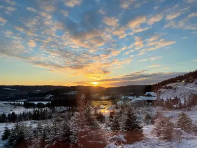 a winter sunset with the sun setting over a town at MYLLA - New cabin - Sauna - Hike - Bike - Canoe- Fishing in Jevnaker