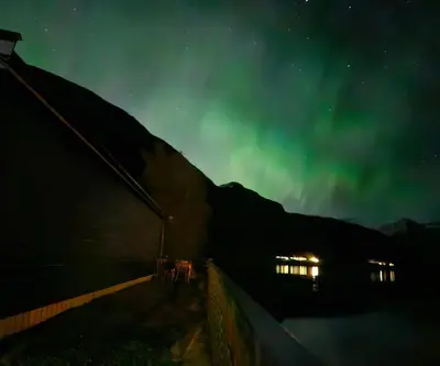 a group of people standing next to a building under the aurora at Lakeside apartment in Stryn