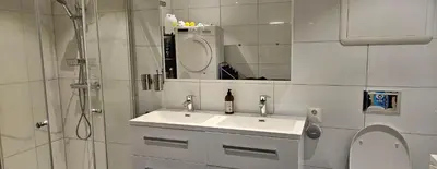 a white bathroom with a sink and a shower at Lakeside apartment in Stryn