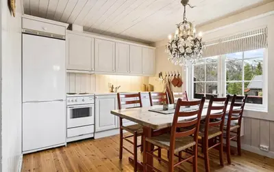 a kitchen with a table and chairs and a white refrigerator at Cabin with ski in-out in Sør-Fron
