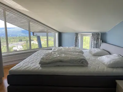 a large bed in a bedroom with a large window at Stor Toppleilighet I Sentrum in Beitostøl
