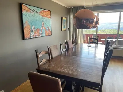 a dining room with a large wooden table and chairs at Stor Toppleilighet I Sentrum in Beitostøl