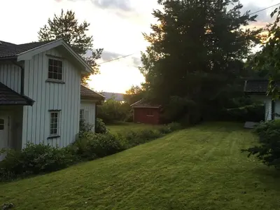 a yard next to a white house with a tree at Welcome to Dalborg, only 1,5 hours from Oslo