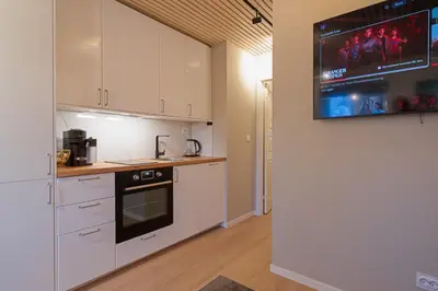 a kitchen with white cabinets and a tv on the wall at EasyStay Nesttun -Free Parking-Buss Nearby - in Bergen
