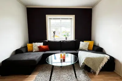 a living room with a black couch and a glass table at Nordic Villa Retreat in Ålesund
