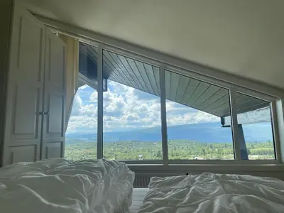 a bed in a bedroom with a large window at Toppleilighet Midt I Beitostølen in Beitostøl