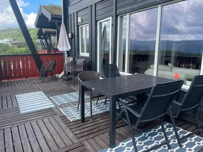 a wooden deck with a table and chairs on it at Toppleilighet Midt I Beitostølen in Beitostøl