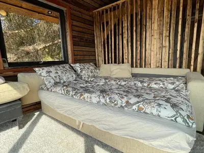 a couch in a room with a bed in a cabin at Forest Hideaway With Scenic View in Fiskå