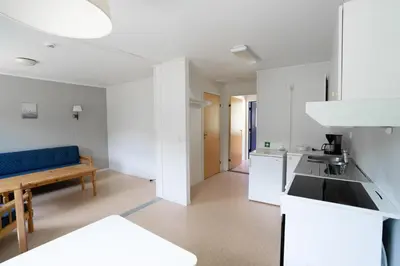 a kitchen with white cabinets and a blue couch at Standard Hytte in Fjæra