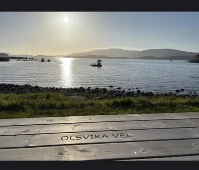 a bench sitting next to a body of water at House close to the beach with a view! in Ålesund