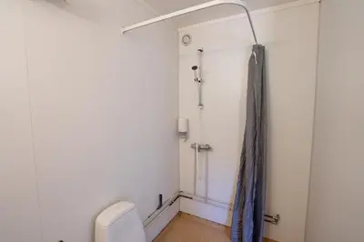 a bathroom with a toilet and a shower curtain at Standard Rom in Fjæra