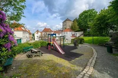 a park with a playground with a slide and a bench at Modern apartment near bryggen - classic architecture in Bergen