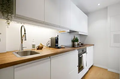 a kitchen with white cabinets and a sink at Modern apartment near bryggen - classic architecture in Bergen