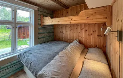 a bed in a wooden room with a window at Beautiful Home In Røn With Sauna in Ron