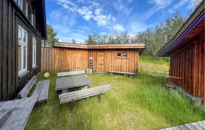 a picnic table and benches in front of a building at Beautiful Home In Røn With Sauna in Ron