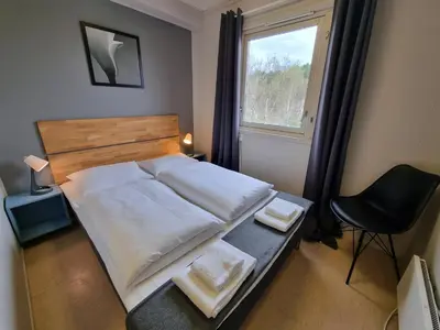 a bedroom with a bed and a chair and a window at Atlanten Turistsenter in Kristiansund