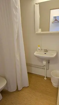 a white bathroom with a sink and a mirror at Atlanten Turistsenter in Kristiansund