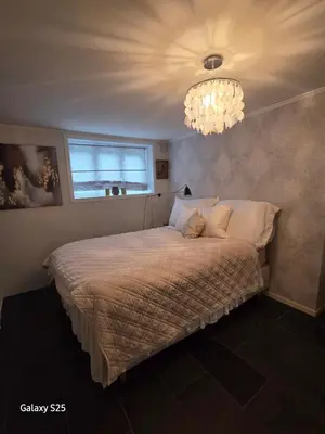 a bedroom with a bed with a chandelier at Quiet home with garden in Bergen