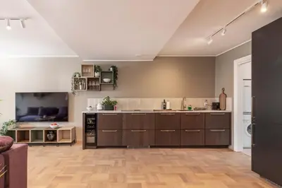 a large kitchen with brown cabinets and a living room at Nice apartment with stunning view over Bryggen in Bergen