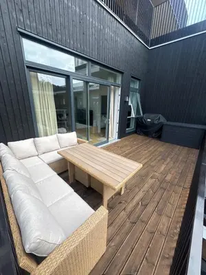a patio with a couch and a table on a deck at Oceanfront Stay, Large Balcony and Rooftop Access in Bergen