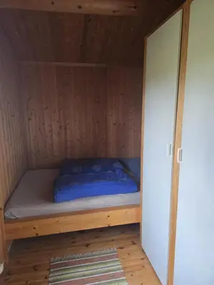 a bed in a small room with a wooden wall at Utsikten in Geilo