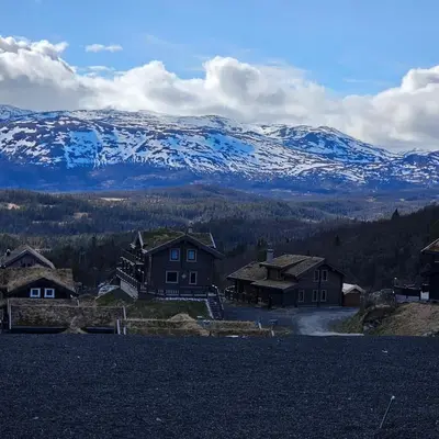 a group of houses with snow covered mountains in the background at Flott hytte i Elgtrakket 9, 3864 Rauland Skisenter - Holtardalen in Torvetjørn
