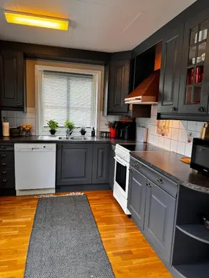 a kitchen with black cabinets and white appliances at Kikays Hygge in Bysheim