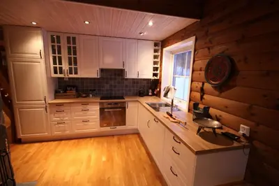 a kitchen with white cabinets and a wooden wall at Spacious Wood Cabin 50 min from Bergen in Eikedalen
