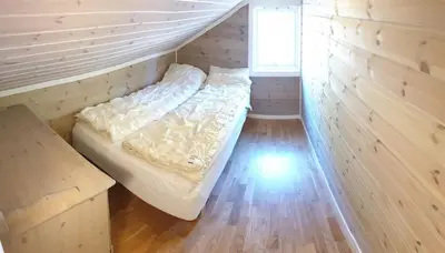 a bed in a small room with a wooden floor at Spacious Wood Cabin 50 min from Bergen in Eikedalen
