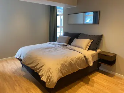 a bedroom with a bed with a tv on the wall at Spacious Modern Apartment City center in Bergen