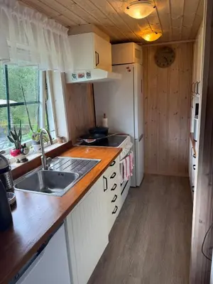 a small kitchen with a sink and a refrigerator at Fantastic cabin in the woods & boat for rental or 2 days free boat on 7 days stay