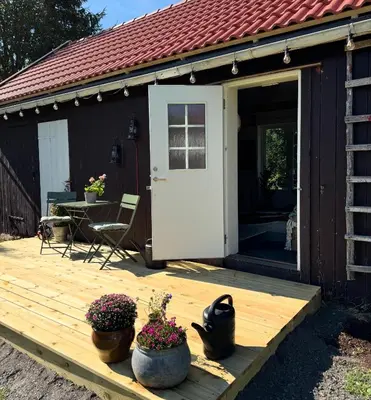 a wooden deck with a door and two pots of flowers at Gjestehus i Hurdal uten innlagt vann Delt bad in Hurdal