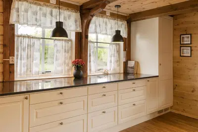 a kitchen with white cabinets and two windows at Family-friendly Cabin with pier - Herdla to Bergen - 40 min in Herlø