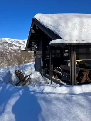 a snow covered cabin with a chair in the snow at Ski in ski out in Geilo, comfortable and family friendly cabin in Geilo