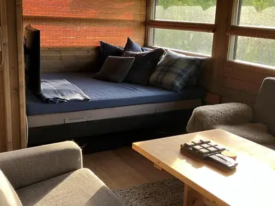 a couch in a room with a table and chairs at Ski in ski out in Geilo, comfortable and family friendly cabin in Geilo