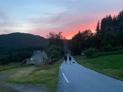 two people walking down a road with a dog at West coast peace in Hyllestad