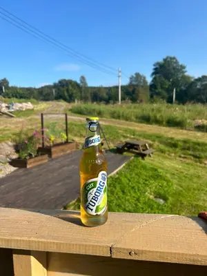 a bottle of beer sitting on top of a wooden table at West coast peace in Hyllestad
