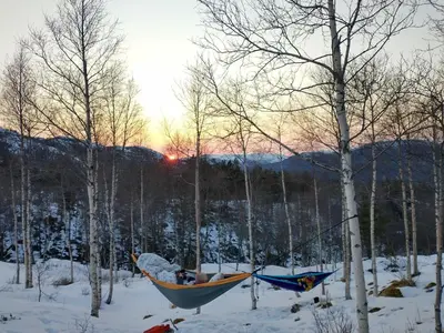 two hammocks in the snow with the sun setting behind trees at Gullingen Cabin Winter Wonderland