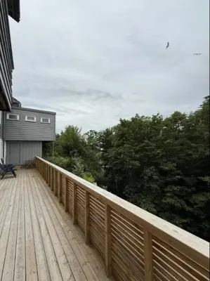 a wooden deck with a bench on top of a house at Moderne leilighet in Bergen