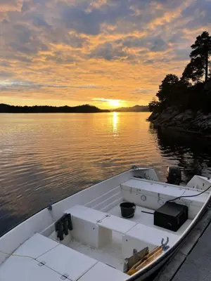 a white boat on the water with a sunset at Haus Harald in Tysnes