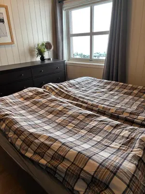 a bed with a plaid blanket on it in a bedroom at Apartment vårstølen in Vossevangen