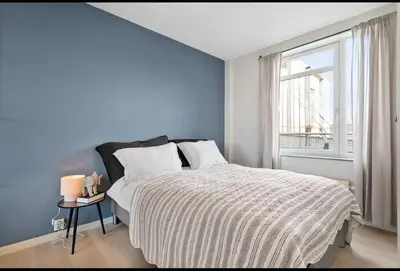 a bedroom with a bed with blue walls and a window at Munkegata 30 Trondheim in Trondheim