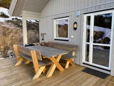 a wooden bench sitting on a deck with a table at Blefjell hytte med fantastisk utsikt in Kongsberg