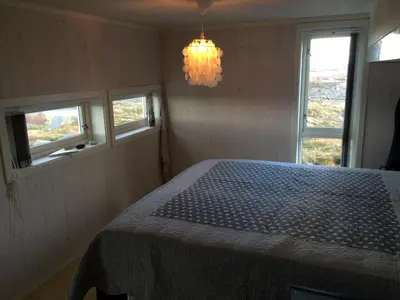 a bedroom with a bed with a chandelier and two windows at Drømmeplassen in Averoy