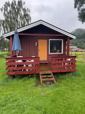 a red cabin with an umbrella in a field at Sjøbakken Fjord Camping AS in Sykkylven