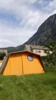 a tent in the grass in front of a house at Fjordshelter Gramping in Tysso