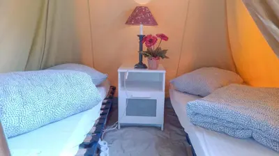 a room with two beds and a table with a lamp at Fjordshelter Gramping in Tysso