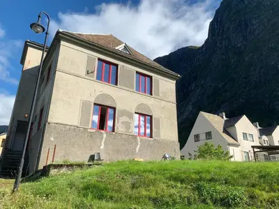 a building with red windows with a mountain in the background at Fjordshelter Gramping in Tysso
